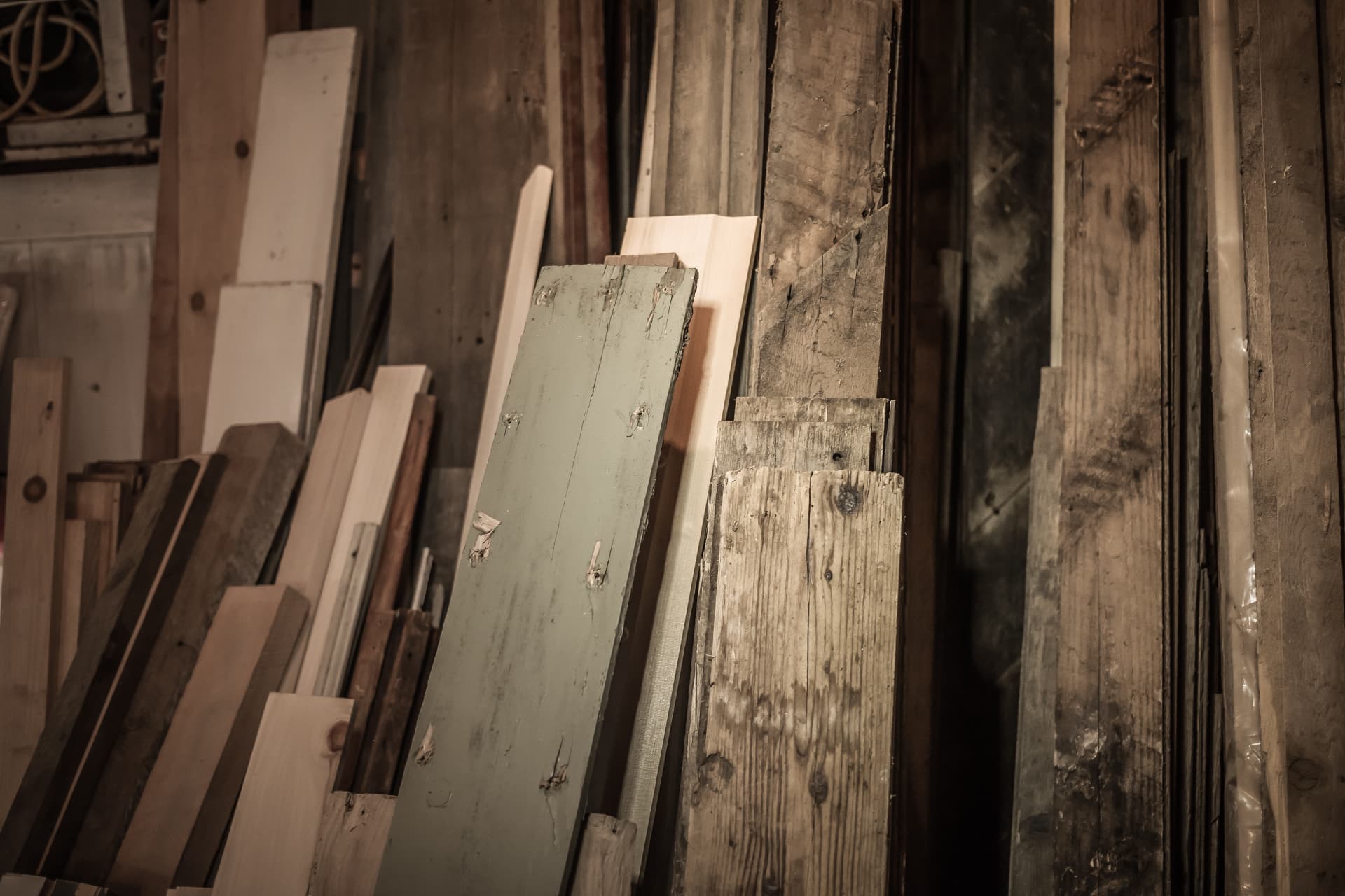 Stacks of rough sawn timber boards leaning against a workshop wall